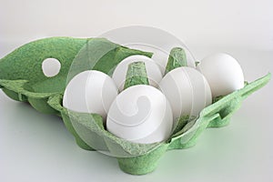 Fresh raw white eggs in a green store cardboard box. Close up studio shot, isolated on white, no people