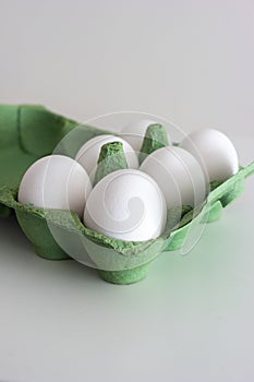 Fresh raw white eggs in a green store cardboard box. Close up studio shot, isolated on white, no people