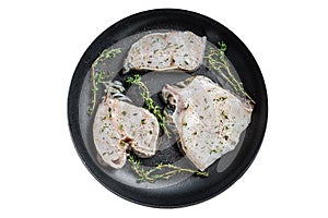 Fresh raw wolffish fillet steaks in a pan with herbs. Isolated, white background. Top view.