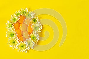 Fresh raw yolks laid out in the shape of an egg decorated with flowers on a yellow background.