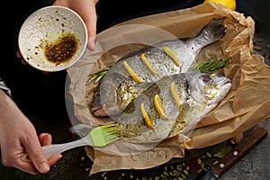 Fresh ready to cook raw bream fish dorado with ingredients and seasonings like rosemary, salt, pepper, lime and olive