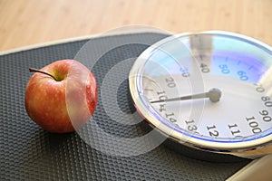 Fresh red apple on an analogue personal scale on a wooden floor, concept for fitness, lose weight diet and healthy eating, copy