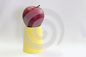 Fresh red apple on cup yellow.
