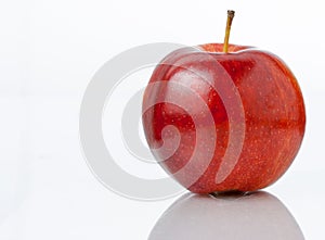 Fresh Red Apple fruit Isolated on White Background. Apple sits on a reflective surface