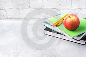 A fresh red apple on a stack of books and notebooks. The concept of a school breakfast snack. Copy space