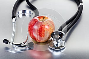 Fresh red apple and stethoscope on stainless steel