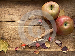 Fresh red apples and cinnamon sticks on wooden background.
