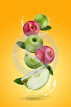 Fresh Red apples and Green apple slices with water splashing on a orange background