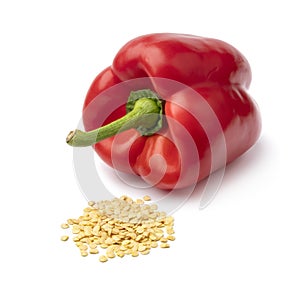 Fresh red bell pepper and a heap of seed in front isolated on white background