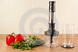 Fresh red bellpepper with herbs and a blender on kitchen table photo
