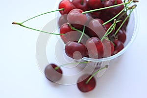 Fresh red cherries in a bowl on light pink powder background. Copy space, minimalistic style
