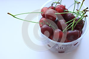 Fresh red cherries in a bowl on light pink powder background. Copy space, minimalistic style