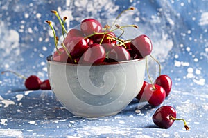 Fresh red cherries in ceramic bowl on blue background.Side view.