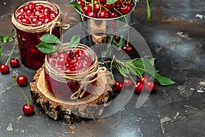 Fresh red cherries fruit on wooden background. Jar of cherry jam and sour cherries. Berries cherry with syrup. Canned fruit. place