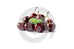 Fresh red cherries lay on white isolated background. Ripe cherry with a leaf of mint on a white background.