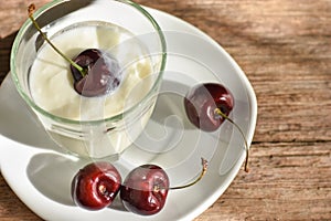 Fresh red cherries and plain yogurt served in white plate. Healthy eating.