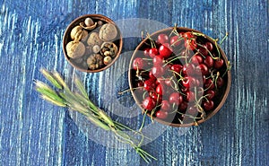 Fresh red cherries and walnuts in a bowl on a wooden blue table