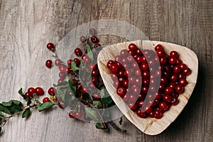 Fresh red cherries in a wooden plate on a wooden table. wooden plate on a wooden background.next to it is a cherry branch with che