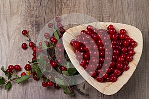 Fresh red cherries in a wooden plate on a wooden table. wooden plate on a wooden background.next to it is a cherry branch with che