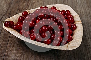Fresh red cherries in a wooden plate on a wooden table. wooden plate on a wooden background. a plate in the form of a triangle. ec