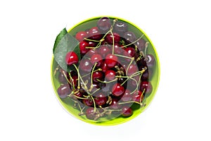 Fresh red cherry on green plate isolated on white. Top view