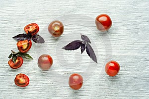 Fresh red cherry tomatoes with basil on a rustic wooden background, selective focus.