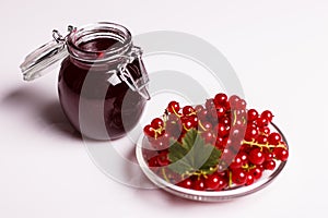 Fresh red currants and jam on a white background