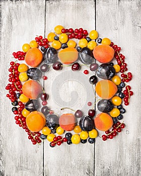 Fresh red currants, plums, blackberries,cherry, blueberries, apricots on a white wood background , top view, frame