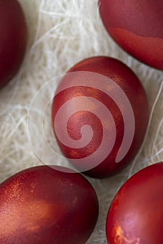 Fresh red eggs and some straw in a wooden crate on a white background.