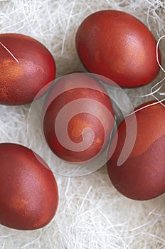 Fresh red eggs and some straw in a wooden crate on a white background.