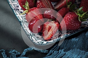 Fresh red fruits on a ceramic plate on a black wooden slate, close up, macro photography