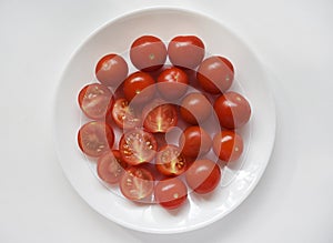 Fresh red fruits of small tomatoes on a glass plate. Juicy chopped cherry tomatoes