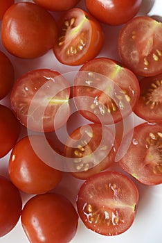 Fresh red fruits of small tomatoes on a glass plate. Juicy chopped cherry tomatoes