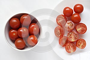 Fresh red fruits of small tomatoes on a glass plate. Juicy chopped cherry tomatoes