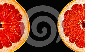 Fresh red grapefruit cut in half on black background