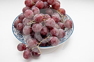 Fresh red grapes in a bowl on a white table