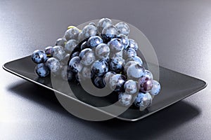 Fresh red grapes bunch on black rectangular dish