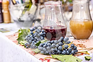 Fresh red grapes with jars of red wine and a traditional young wine burciak - burcak