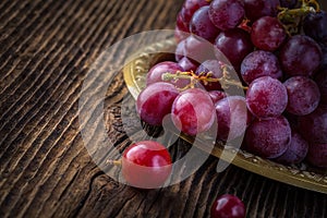 Fresh red grapes in old bowl on wooden table