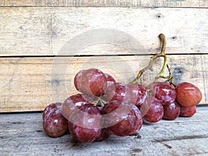 Fresh red grapes placed on brown wood.