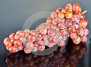 Fresh red grapes with water drops on gray background