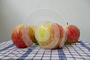 Fresh red-green apples, with water drops on surface of peel, lying picturesquely on white waffle fabric textile tablecloth. photo