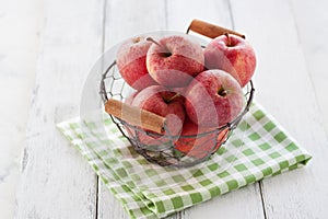 Fresh red juicy apples in a basket on a green textile on a wooden background