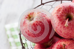 Fresh red juicy apples in a basket on a green textile on a wooden background