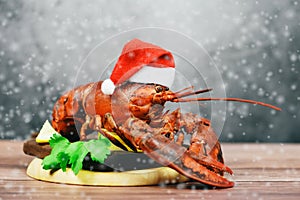 Fresh red lobster with christmas hat shellfish cooked in the seafood restaurant - Steamed lobster dinner food on wooden christmas