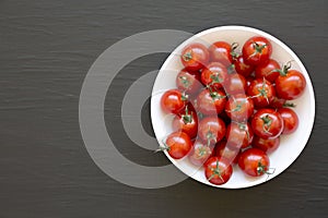 Fresh Red Organic Cherry Tomatoes in a Bowl on a black background, top view. Copy space