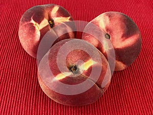 Fresh red peaches on red cloth napkin on table.