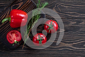 Fresh red pepper and red tomatoes on a wooden board