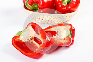 Fresh red peppers with wicker basket lying on white background, healthy nutrition concept