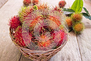 Fresh red rambutan sweet delicious fruit in basket on wood table. Tropical fruit tree, native to South - East Asia , cultivated in